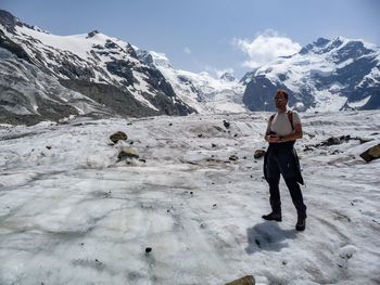 Full length of hiker standing on snow covered mountain against sky