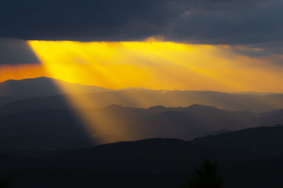 Scenic view of silhouette mountains against orange sky