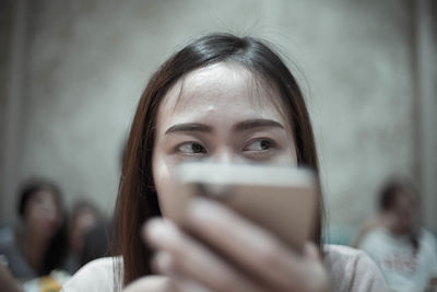Close-up portrait of smiling girl holding mobile phone
