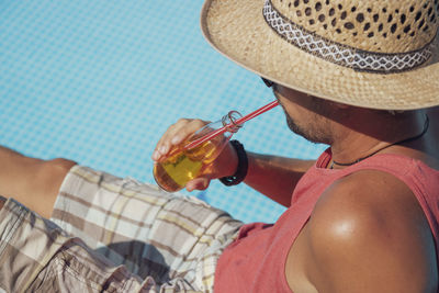 Man drinking juice in bottle by poolside