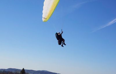 Low angle view of person paragliding against sky