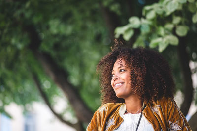 Close-up of thoughtful mid adult woman with curly hair looking away at park