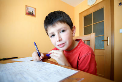 Portrait of boy holding pencils on table