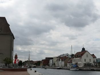 Canal amidst buildings in city against sky