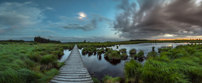 Boardwalk over lake against sky