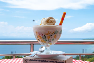 Close-up of drink with ice cream against sky