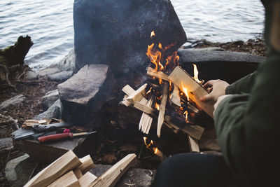 Man making campfire on lakeshore