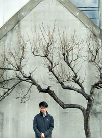 Portrait of man standing by bare tree