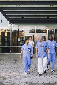 Multiracial male and female doctors in scrubs leaving hospital