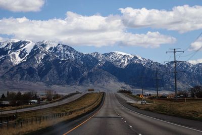 Road leading towards snowcapped mountains against sky