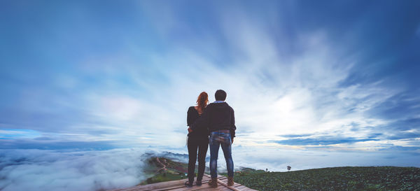 Rear view of man standing on mountain against sky