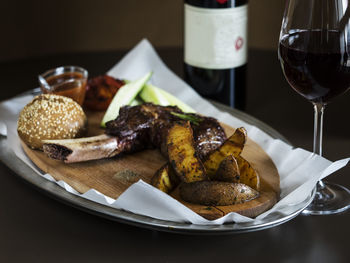 Grilled steak on bone veal with baked potatoes and bun served in tray on table