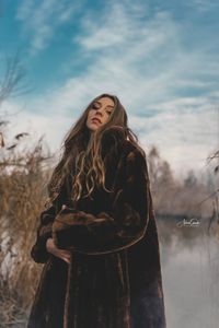 Woman standing in snow against sky during winter