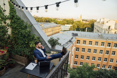 Male professional talking on mobile phone while relaxing in balcony