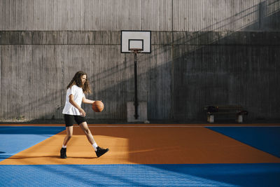 Female basketball player dribbling ball at sports court