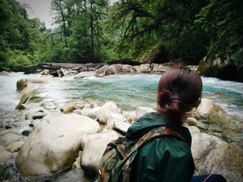 Side view of woman sitting on riverbank