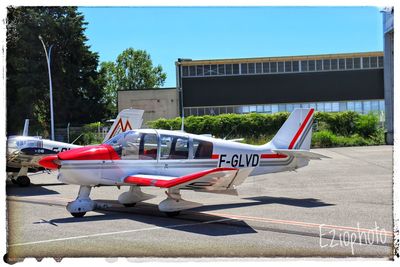 Airplane on airport runway against sky