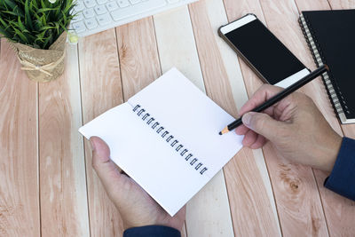 Cropped hand of woman using mobile phone on table