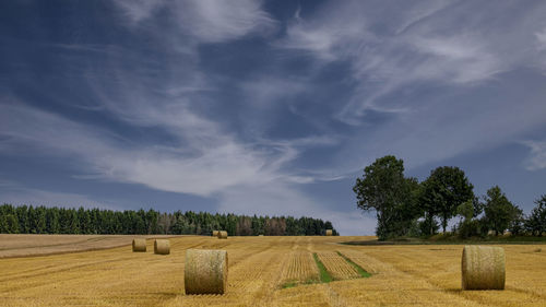 Hay bales on field against sky