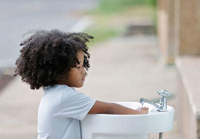 Side view of girl washing hands outdoors