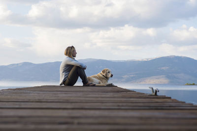 Man with dog standing on mountain against sky