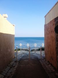 Gate at walkway against houses against sea