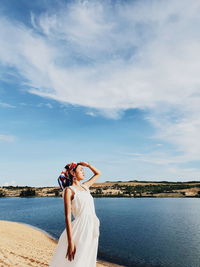 Woman standing by sea against sky