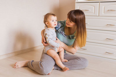 Happy friends sitting on wooden floor