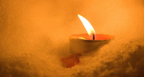 Close-up of lit candle against wall