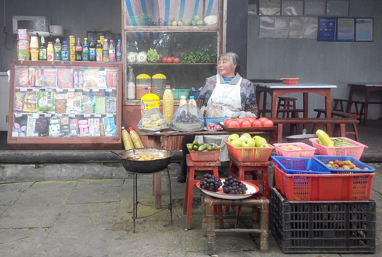 retail, one person, real people, food and drink, food, variation, front view, choice, container, market, for sale, casual clothing, small business, store, business, large group of objects, looking at camera, retail display, freshness