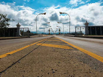 Surface level of road against cloudy sky