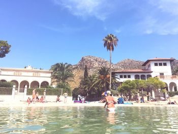 People swimming in pool against sky