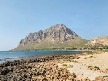 Scenic view of sea and mountains against clear sky