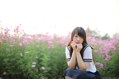 Portrait of woman standing by pink flowering plants