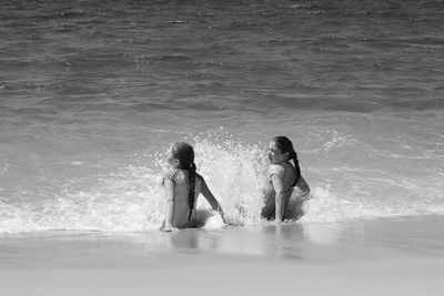 Rear view of siblings enjoying on shore at beach