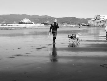 Rear view of woman walking on beach against sky