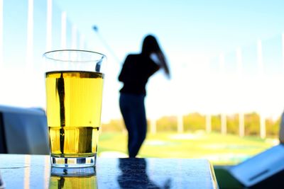 Close-up of man with drink standing against yellow sky