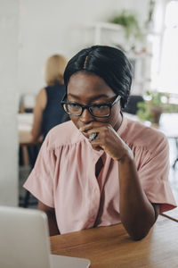 Tensed young businesswoman looking at laptop while sitting at desk in office