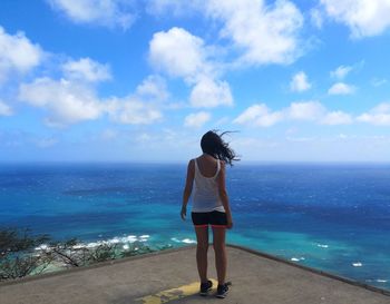 Rear view of woman looking at blue sea against sky