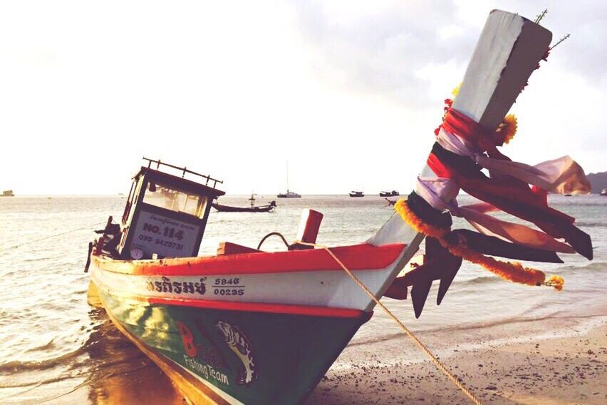 MAN ON BOAT MOORED AT BEACH