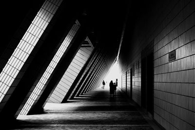 Silhouette people walking on footpath in illuminated building