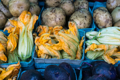 High angle view of containers filled with squash blossoms for sale at farmers market stall
