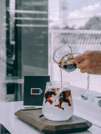 Pouring black coffee into glass with ice