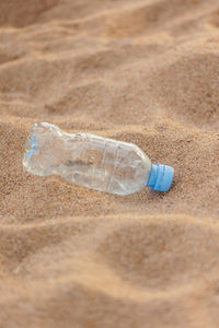 Close-up of water bottle on sand