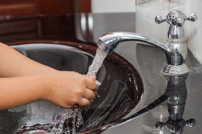 Midsection of woman with faucet in bathroom