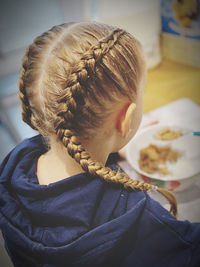 Rear view of girl with braided hairstyle at home