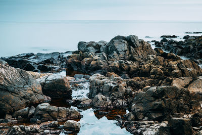 Rocks by sea against clear sky