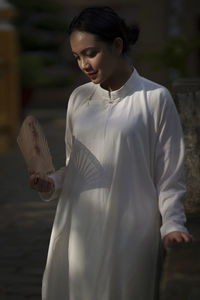 Young woman looking down while standing against white background