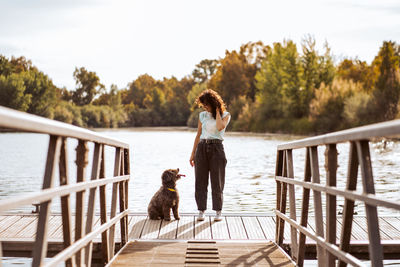 Woman with dog standing on jetty