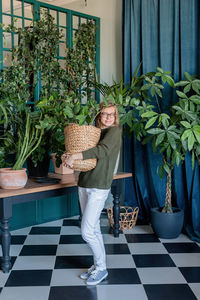 Young woman in green sweater taking care of the plants at home